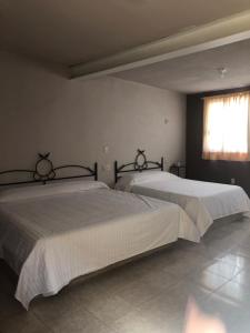 2 camas en un dormitorio con ventana en Hotel El Pacifico, en Morelia