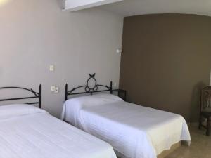 a bedroom with two beds and a chair at Hotel El Pacifico in Morelia