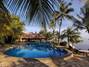 una piscina en el complejo con palmeras en Relax Bali Dive & SPA ocean front resort, en Tulamben