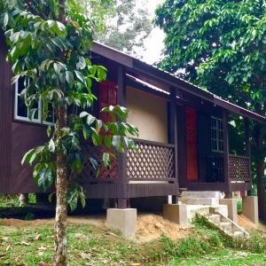 una pequeña casa con un porche y un árbol en Lang Buana Eco Park, en Jerantut