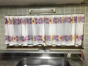 a kitchen window with a curtain with flowers on it at STAY Sakura in Bibai +38 photos