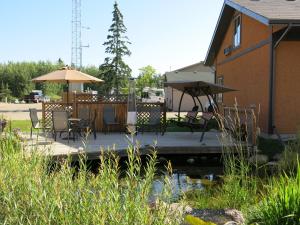 eine Terrasse mit Stühlen und Sonnenschirmen neben einem Haus in der Unterkunft Village Creek Country Inn in Westerose