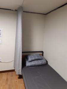 a bed in a room with a white wall at Able Guesthouse Hongdae 2 in Seoul