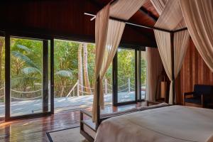 a bedroom with a bed and large windows at Taj Exotica Resort & Spa, Andamans in Havelock Island