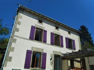 a white building with purple shutters on it at 38 Friaudour in Saint-Pardoux