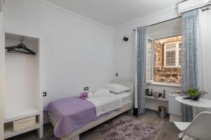 ein weißes Schlafzimmer mit einem Bett und einem Fenster in der Unterkunft Guest House Tomasi One in Dubrovnik