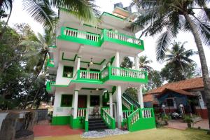 a green and white house with palm trees at Casa Margarida in Calangute