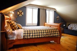 Auberge la maison sous les pins في Saint-Joseph-de-la-Rive: غرفة نوم مع سرير وبطانية مقلية