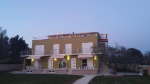 un gran edificio amarillo con un faro en la parte superior en Apartments Nogic en Peroj