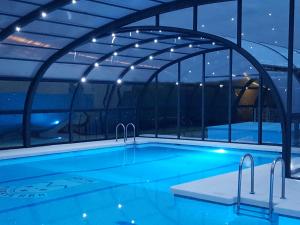 a swimming pool with an arched roof at night at Mirasierra in Santo Tomé del Puerto