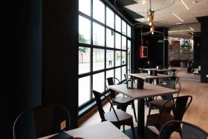 a restaurant with tables and chairs and a large window at Rener Hotel Los Campones in Gijón