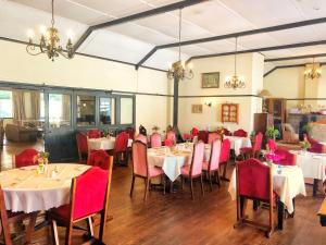 a dining room with tables and red chairs at Green Lantern Inn in Van Reenen