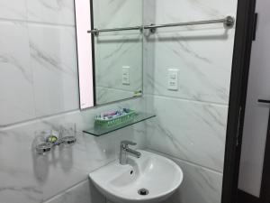 Baño blanco con lavabo y espejo en Lea House Ha Long, en Ha Long