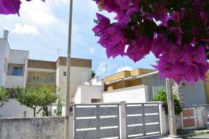 a fence in front of houses with purple flowers at Appartamento Itaca - Le vie di Omero in Torre dell'Orso
