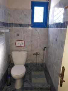 a bathroom with a toilet and a window at Karabo Hotel in Livadi Astypalaias