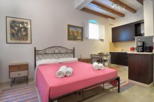 a bedroom with a pink bed with towels on it at Milonas Studios in Corfu +13 photos