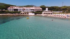 a large building in the water next to a beach at Hotel Punta Negra in Alghero