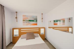 a bedroom with two beds and paintings on the wall at La Pardela Exclusive Apartamentos in Caleta de Sebo