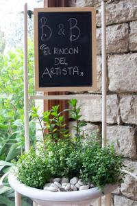 un cartel en una pared con una olla de plantas en El Rincon del Artista, en Soiano del Lago