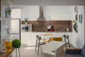 a kitchen with white cabinets and a table and chairs at La Pardela Exclusive Apartamentos in Caleta de Sebo