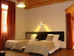 a bedroom with two beds and a light on the wall at Apartamentos Kósmos in Horta