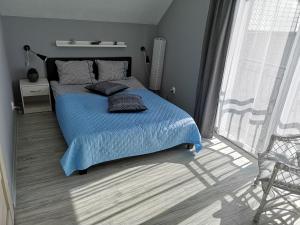 Schlafzimmer mit einem Bett mit blauer Bettwäsche und einem Fenster in der Unterkunft Domki Białogóra in Białogóra