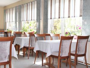 a dining room with white tables and chairs and windows at Hotel Gasthuus Spieskamer in Hasselberg