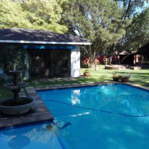 a swimming pool with a fountain in a yard at Azrielle Guesthouse in Sasolburg