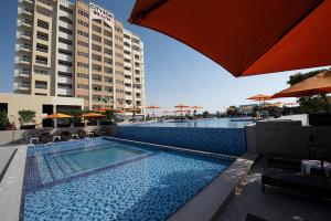 a swimming pool with a large blue umbrella at City Stay Beach Hotel Apartments - Marjan Island in Ras al Khaimah