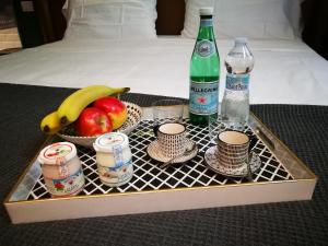 a tray with fruit and two bottles and cups and drinks at OFFICINA TESINI Guest Rooms Verona in Verona