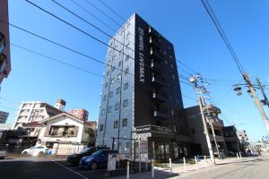 a tall building on the corner of a street at HOTEL LiVEMAX Minamihashimoto Ekimae in Sagamihara