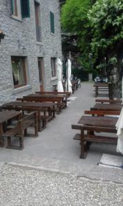 uma fila de bancos de madeira em frente a um edifício em La Foresta Albergo Ristorante Pizzeria em Badia Prataglia