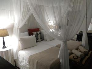 1 dormitorio con 1 cama blanca con dosel en St Lucia Kingfisher Lodge, en St Lucia