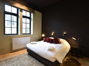 een slaapkamer met een groot bed met witte lakens en rode kussens bij Luxurious Apartment in Nieuwpoort with Jacuzzi in Nieuwpoort