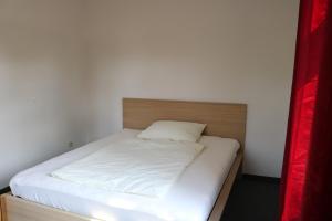 a bed with white sheets and a wooden headboard at Ferienwohnung Post in Ottendorf-Okrilla