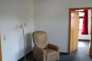 una silla marrón en una habitación con lámpara en Ferienwohnung Post, en Ottendorf-Okrilla