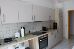 cocina con armarios blancos y encimera en Ferienwohnung Post, en Ottendorf-Okrilla