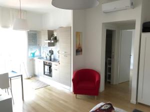 a living room with a red chair and a kitchen at La Casa Di Camp - Apartment in Rome