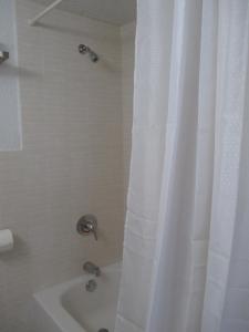baño con ducha con cortina blanca en Shalimar Motel, en Miami