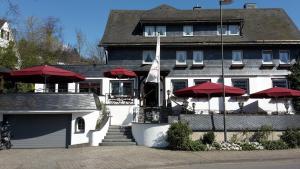 un hotel con sombrillas rojas frente a un edificio en Land-gut Hotel zur Brücke garni, en Drolshagen