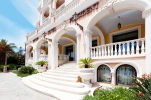 a large white building with stairs and potted plants at Grand Hotel President in Olbia