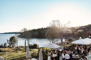 a group of people sitting at tables near a body of water at Destination Bokenäset in Uddevalla