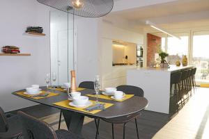 a dining room with a table and chairs and a kitchen at Luxury Apartments by Atelier VO2 max with Large Terrace and Parking 10 min from Beach in Knokke-Heist