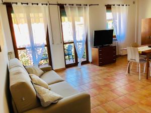 een woonkamer met een bank en een tafel met een televisie bij APPARTAMENTO PESCHIERA - zona Ospedale Pederzoli in Peschiera del Garda