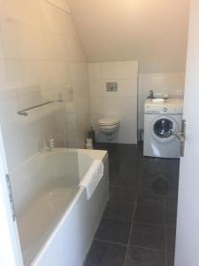 a bathroom with a tub and a washing machine at Rue de la Gare in Prouzel +23 photos