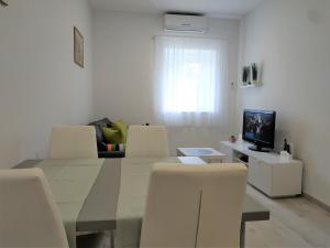 扎达尔Holiday Home Arbanase的客厅配有桌子和白色椅子