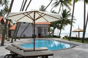 an umbrella and a bench next to a swimming pool at Muine Century Beach Resort & Spa in Mui Ne
