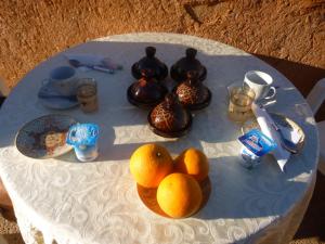 una mesa con naranjas y tazas de té. en iskki-asnfou, en Tafraoute
