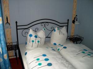 uma cama com lençóis brancos e flores azuis em La Petite Provence em Leisnig