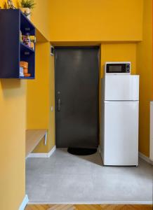a kitchen with a white refrigerator and a black door at Sunburst Apartment in Tbilisi City
